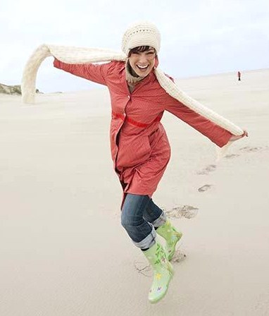 Germany, St Peter-Ording, North sea, Woman having fun in sand dunes, smiling, portrait