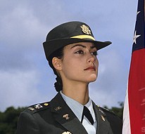 Hawaii, Woman Lieutenant, U.S. Army, in uniform, standing next to U.S. flag.